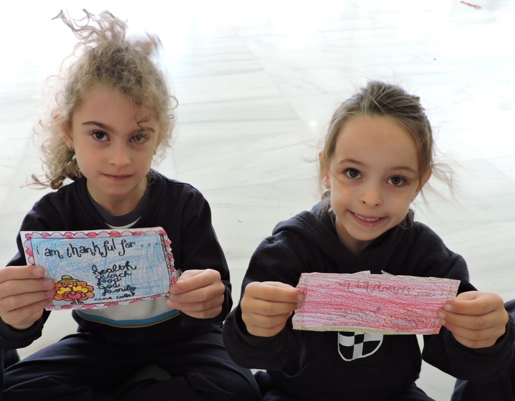 Dos niñas posan con un mensaje para dar gracias a Dios